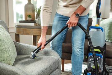 Using Hose on end of carpet cleaner to deep clean stain on couch cushion.