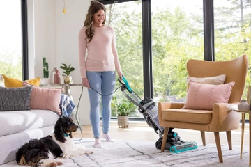 CleanView Swivel Pet Reach Vacuum vacuuming under furniture on area rug.