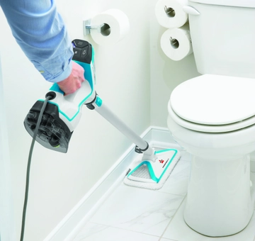 Using PowerFresh Slim 3-in-1 Steam Mop to mop tile flooring between wall and toilet in bathroom.