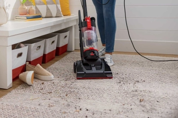 CleanView Compact Upright Vacuum vacuuming dirty from entry way area rug.