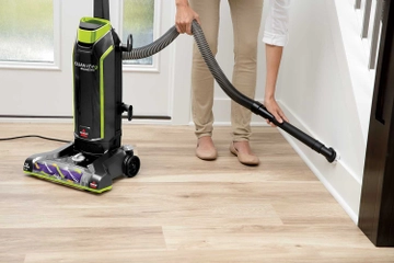 Using Hose with Dusting Brush to vacuum baseboards.